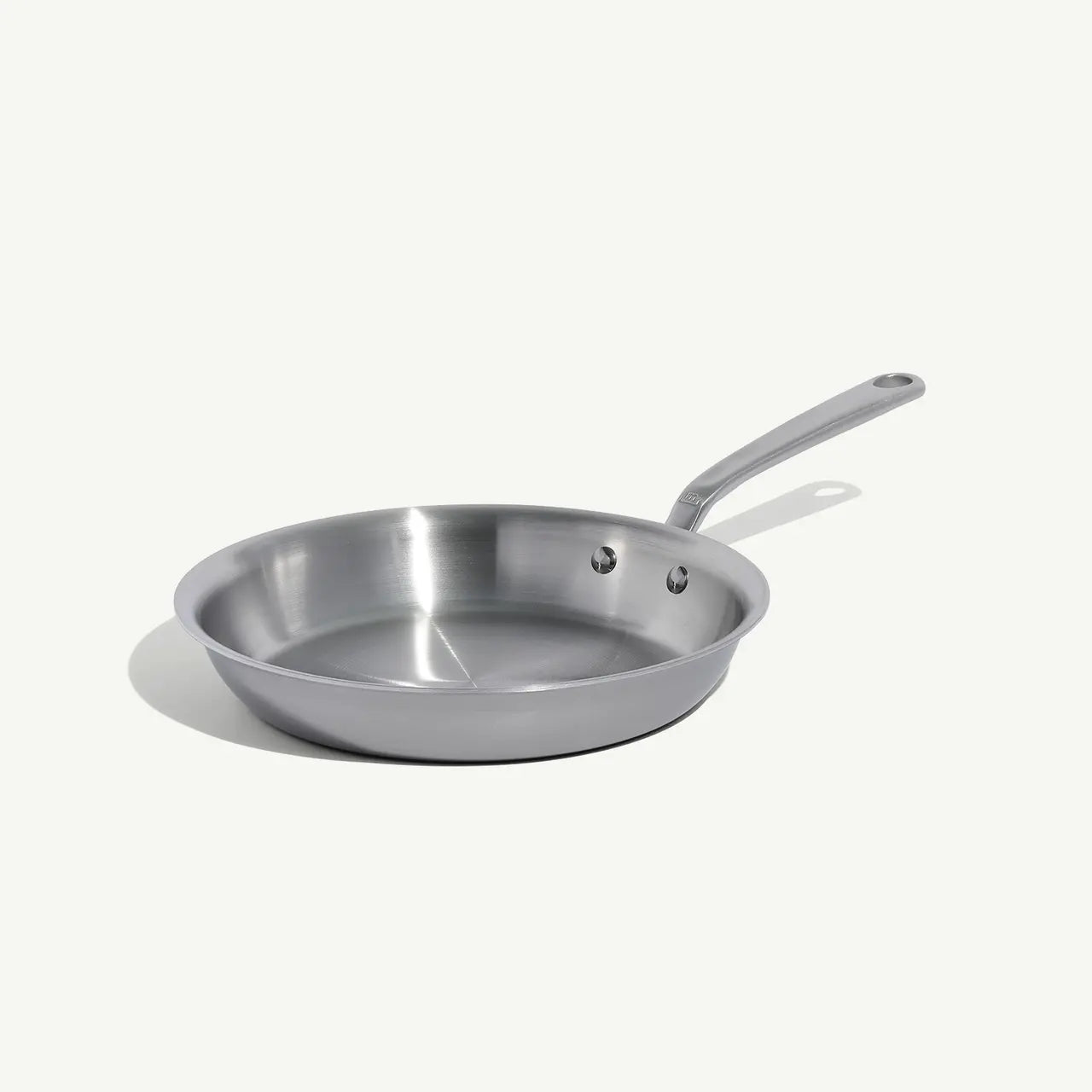A side view of a stainless steel frying pan with a stay-cool handle.