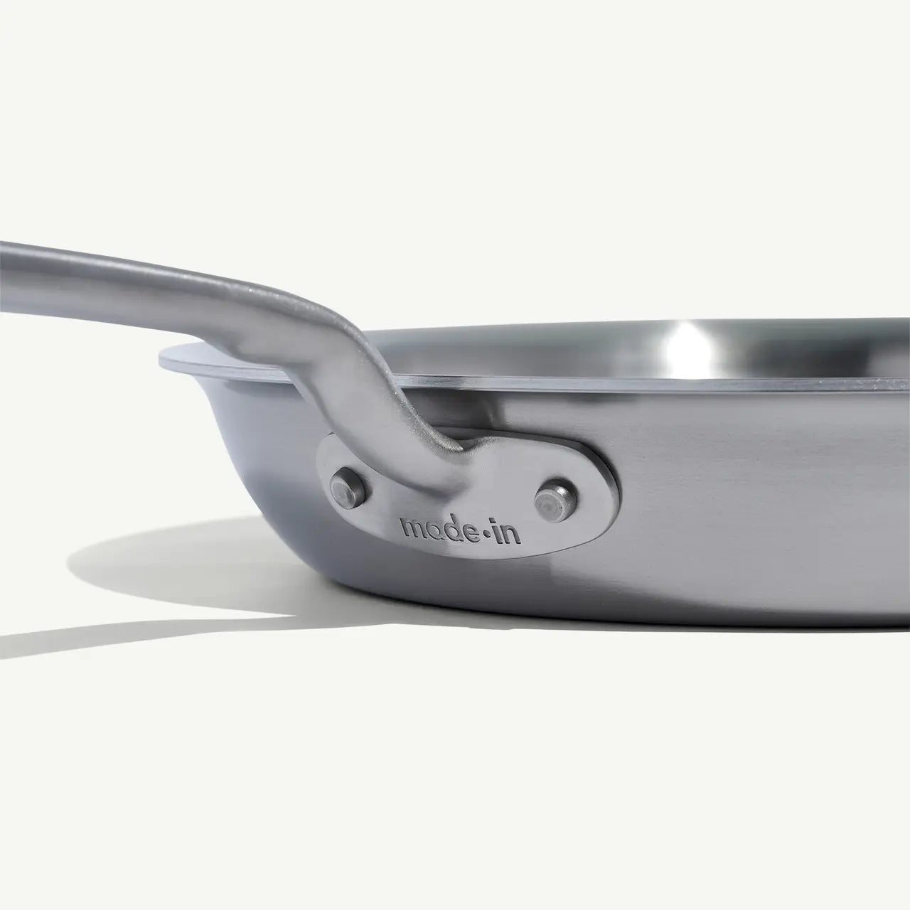 A close up view of a stainless steel frying pan with a stay-cool handle.