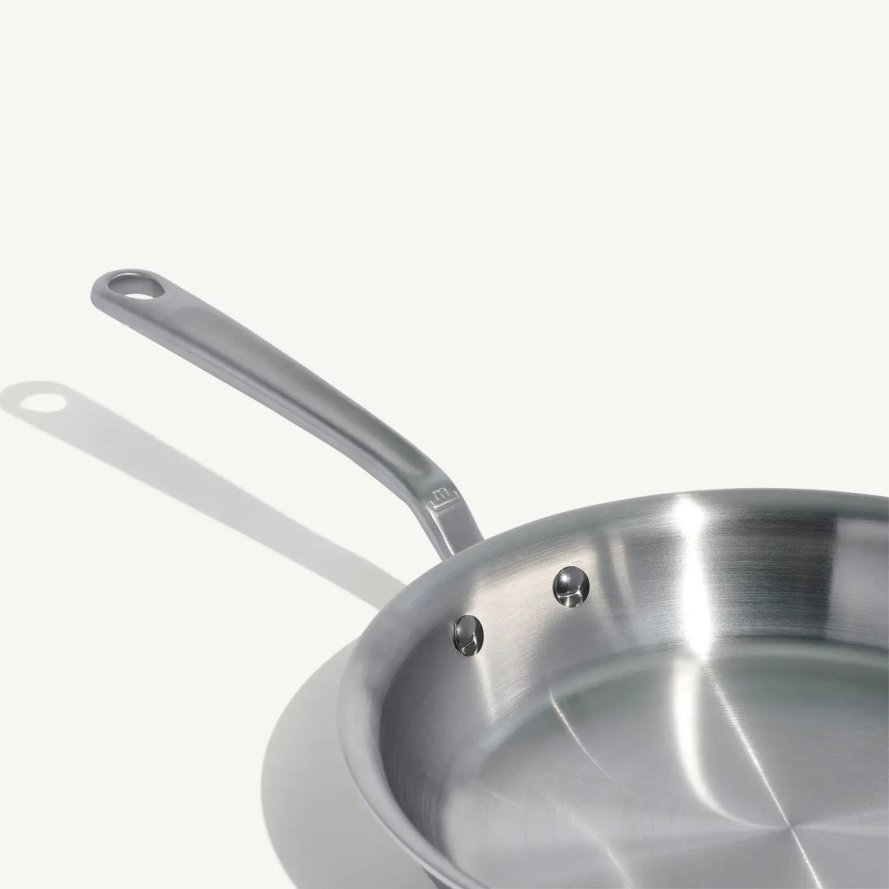 A handle view of a stainless steel frying pan with a stay-cool handle.