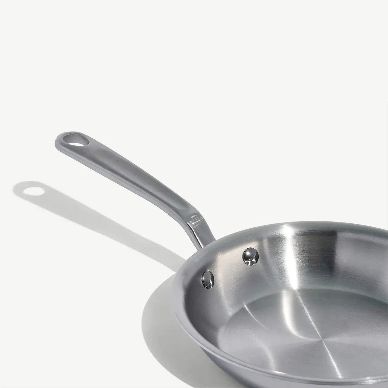 A stainless clad frying pan with a stay-cool handle, suitable for gas, electric, and induction cooktops on a white background.