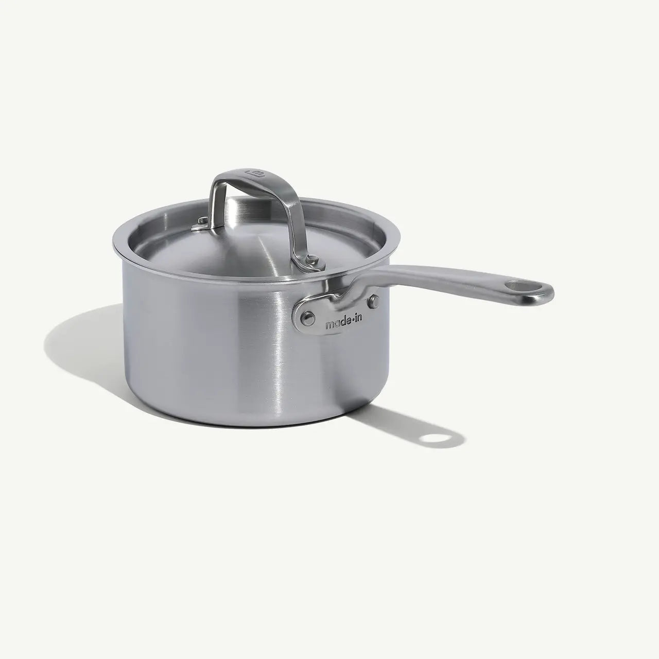 A silver stainless clad saucepan with a lid and a stay-cool handle, suitable for cooking sauces and soups.