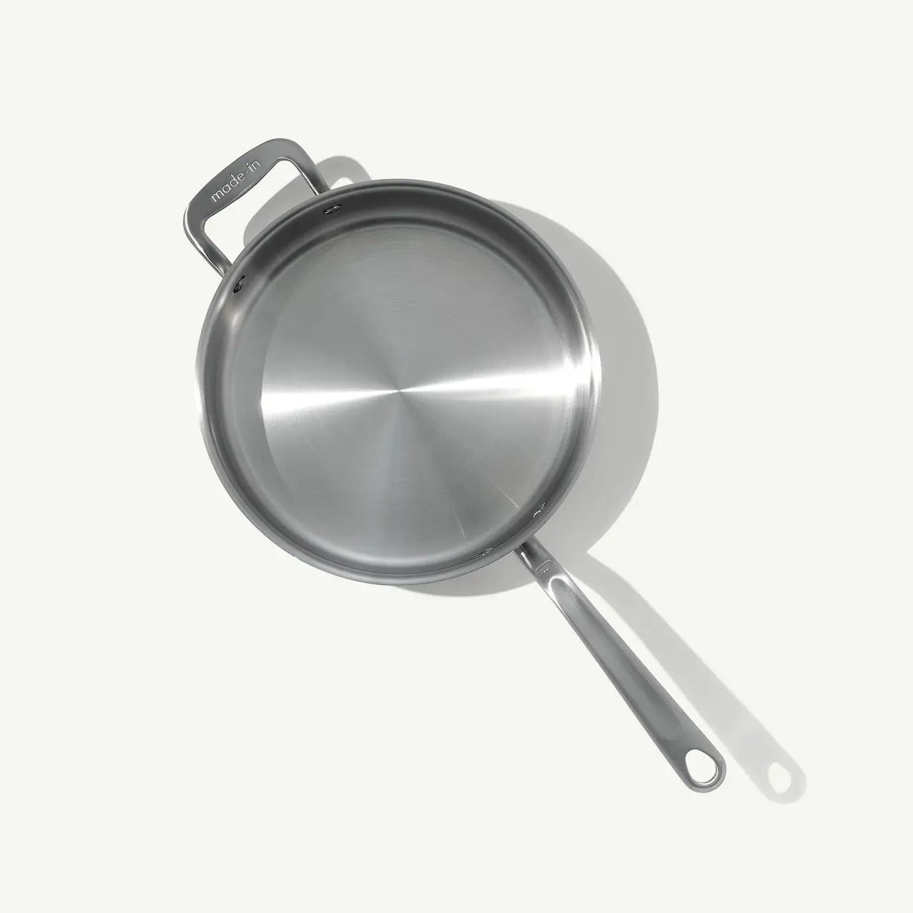 A stainless steel sauté pan with a lid and stay-cool handle, on a white background.