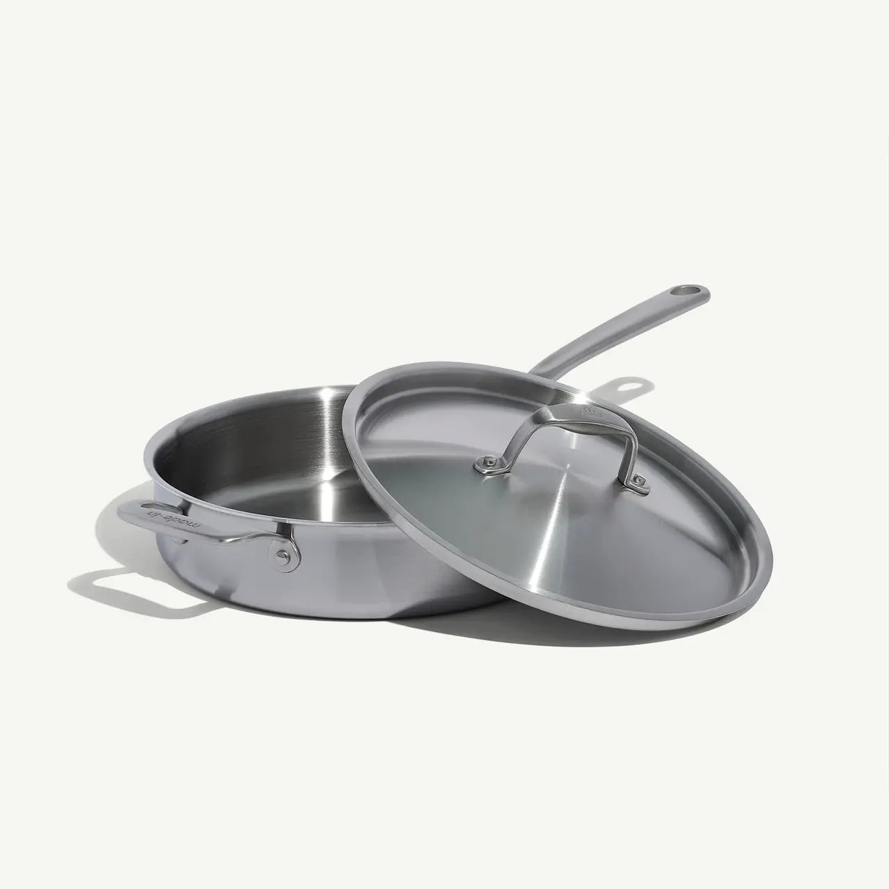 A stainless steel sauté pan with a lid and stay-cool handle, on a white background.
