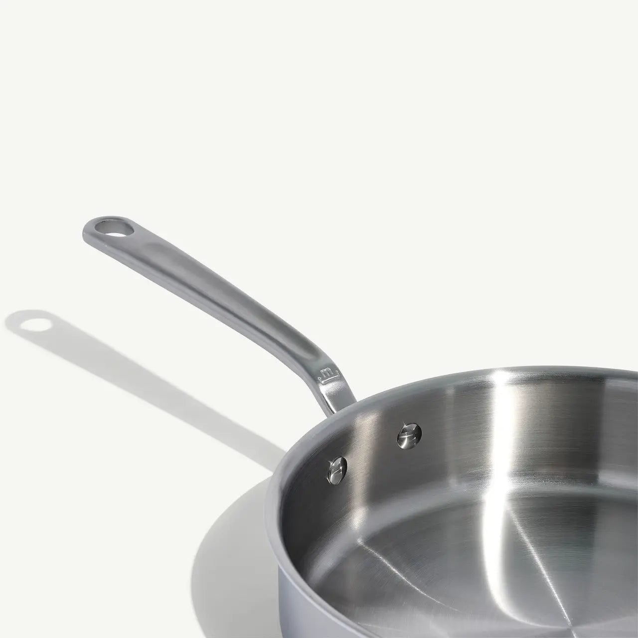 A stainless steel sauté pan with a lid and stay-cool handle, on a white background.