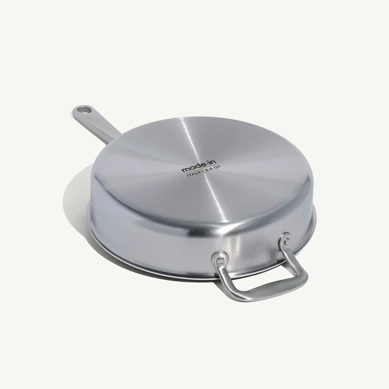 A stainless steel sauté pan with a lid and stay-cool handle, on a white background.