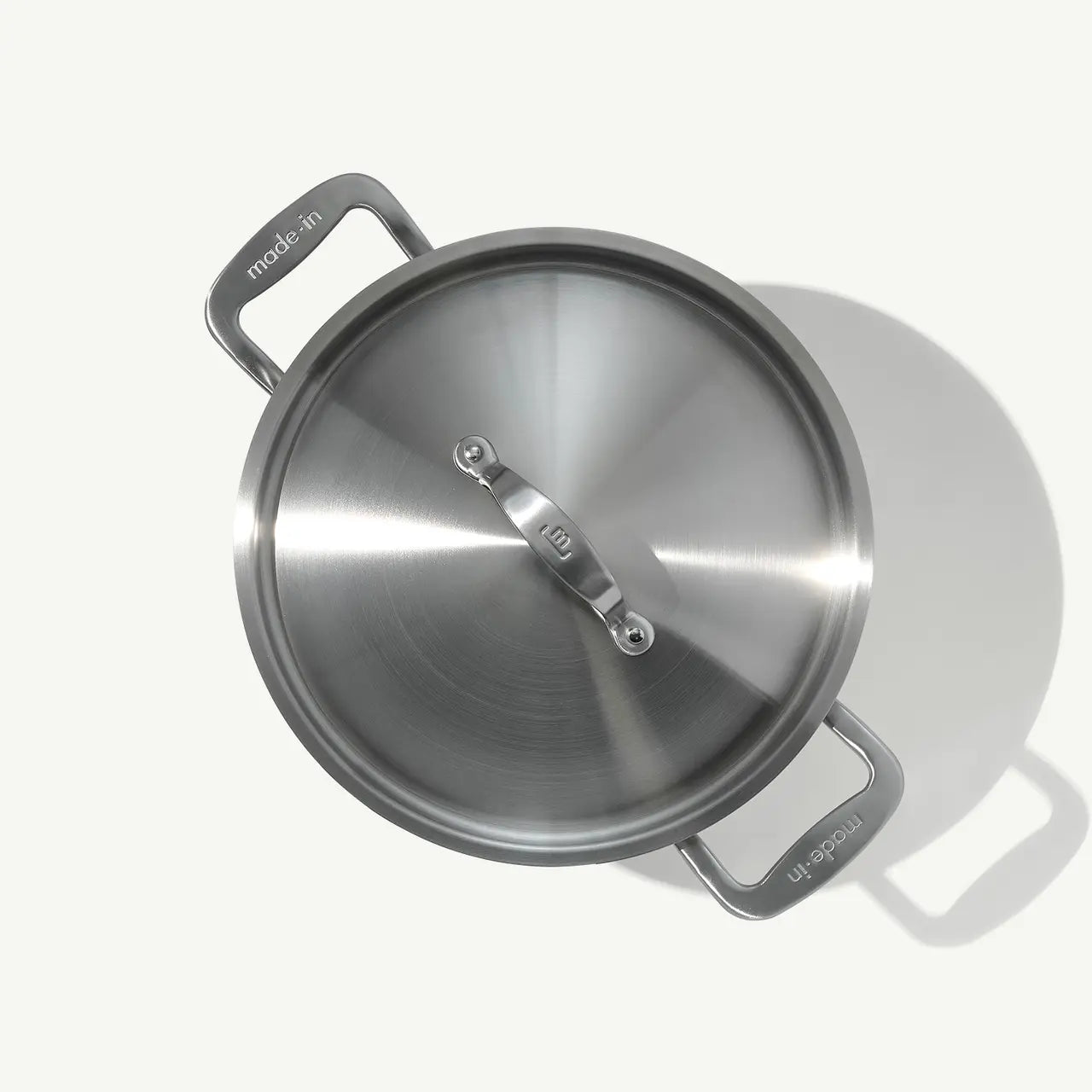 A silver stainless clad stock pot with lid, featuring two handles and a fitted lid, on a white background.