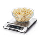 Digital kitchen scale with a bowl of popcorn on a white background