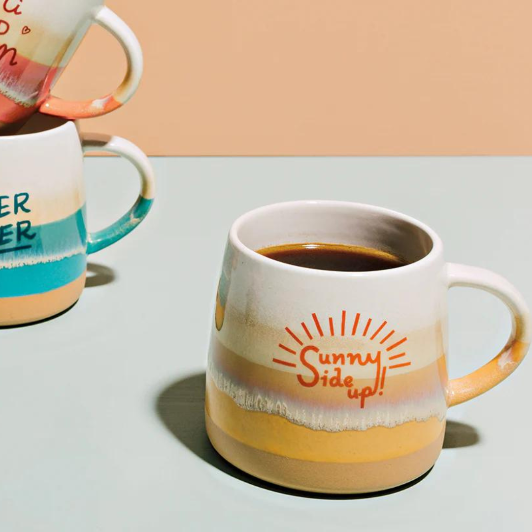 the Sunny Side Up Mug from Danica Jubilee! This cheerful 12oz glazed stoneware mug features sandy ombre stripes and the cheerful phrase “Sunny Side Up!” in vibrant orange.