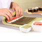 Person making sushi with a rolling mat on a table with ingredients and a wooden board in the background.