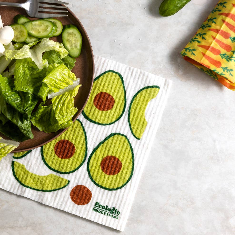 Colorful reusable paper towels with avocado design on a table with salad and cucumber.