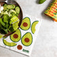 Colorful reusable paper towels with avocado design on a table with salad and cucumber.