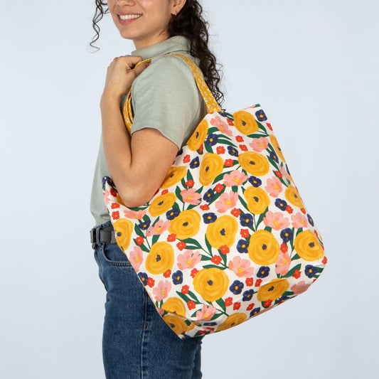 Person carrying a floral-patterned bag on a plain background