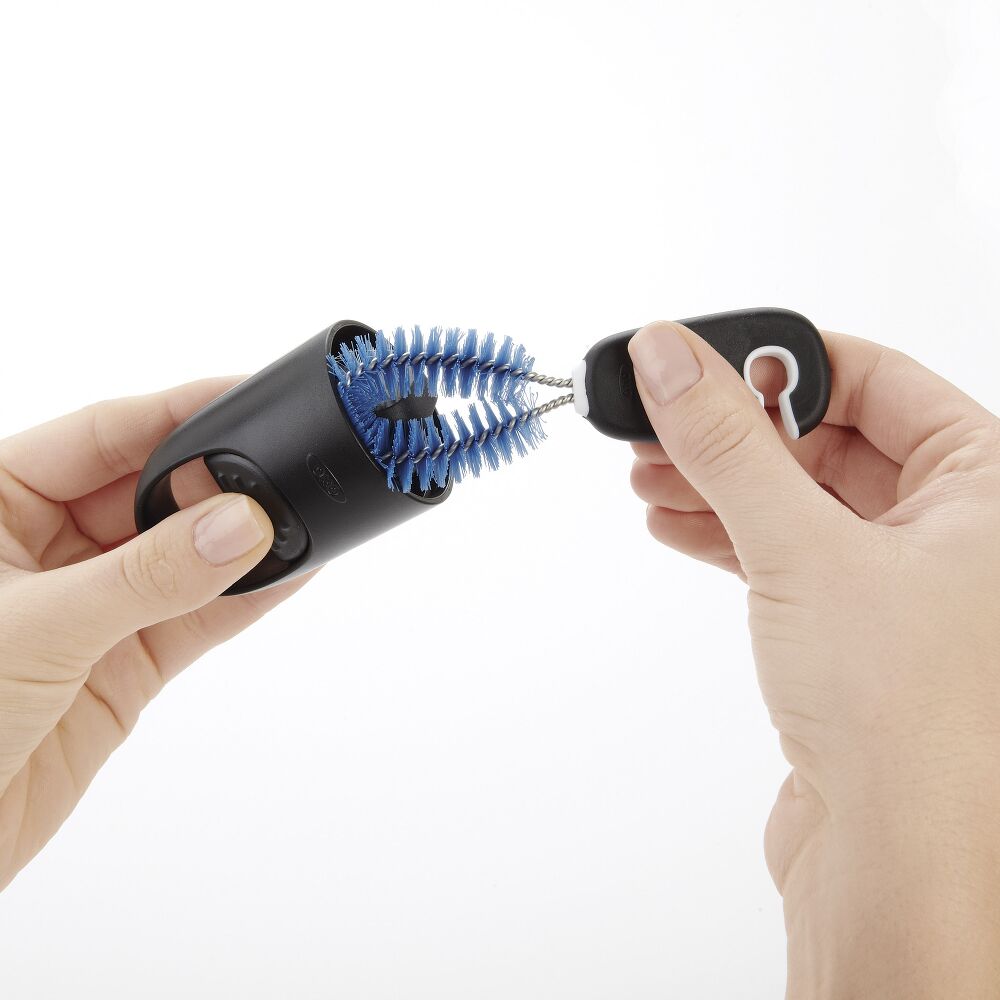 Small blue brush being used to clean a black cap. 