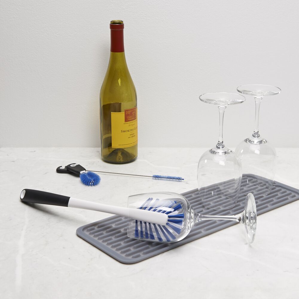 Brush being used to clean a wine glass on a white surface. 