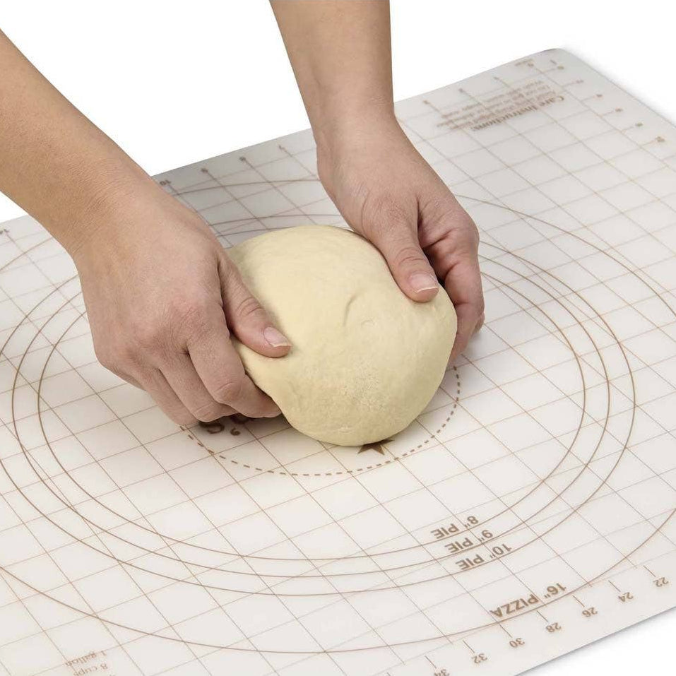 Person kneading dough on a pizza peel mat with measurements.