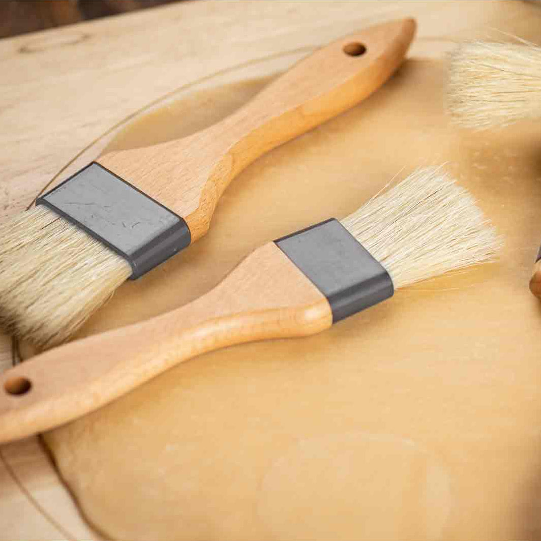 Set of four wooden brushes with bristle heads on a wooden surface