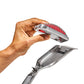 Hand holding a metal shaver head with red bristles against a white background