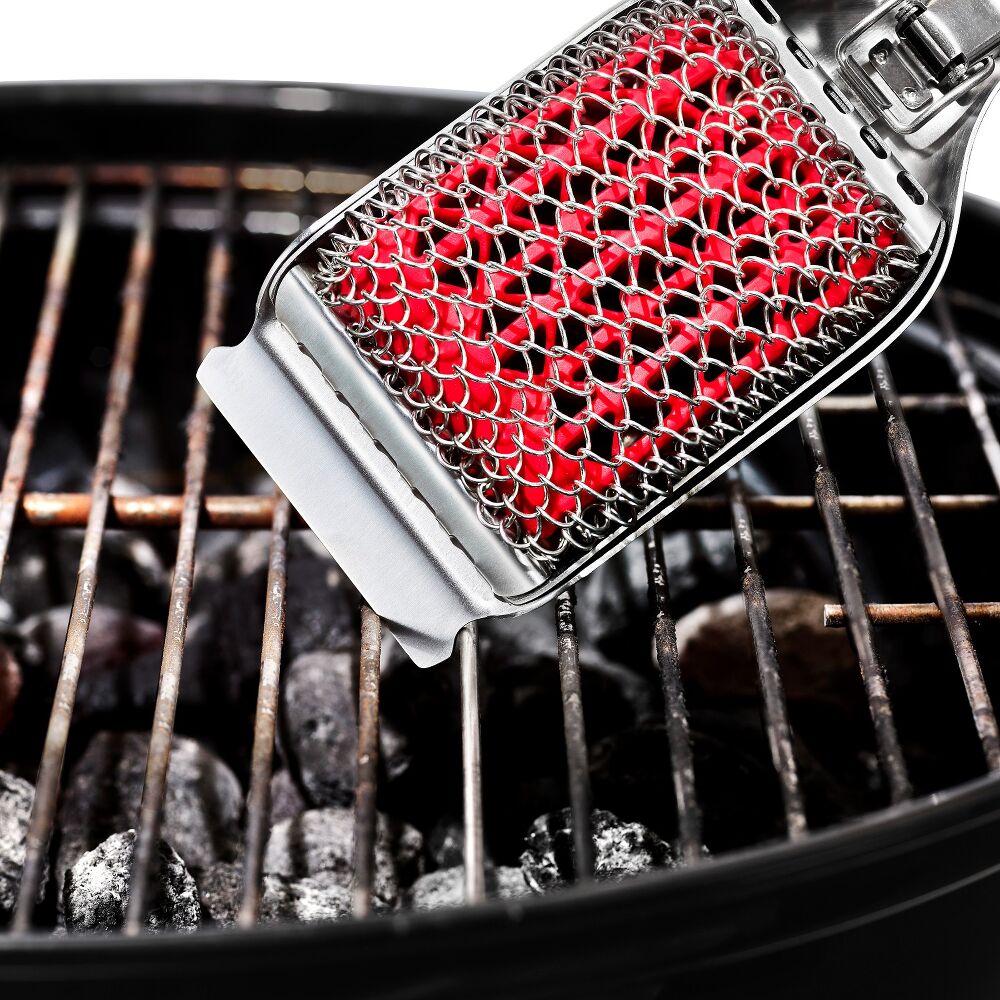 Barbecue grill cleaning brush with red bristle head on a grill