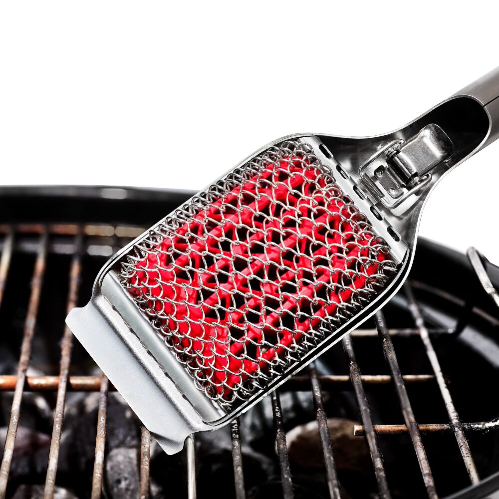 Red grill brush with a metal handle on a grill