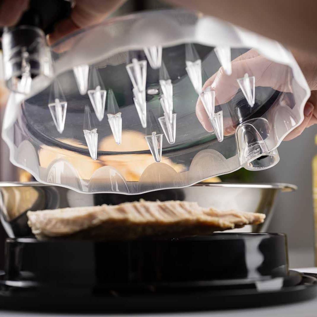 Person using a transparent egg holder with multiple compartments on a kitchen counter.