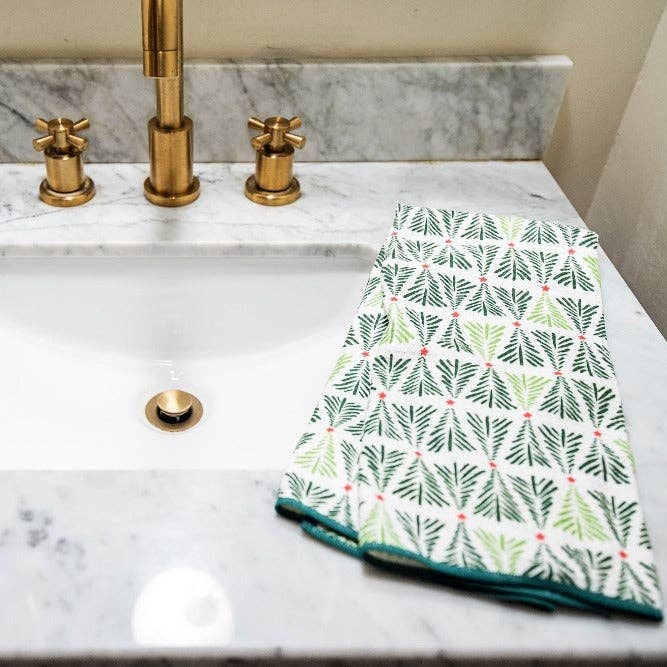 Bathroom sink with marble countertop and gold faucet, featuring a green patterned towel.