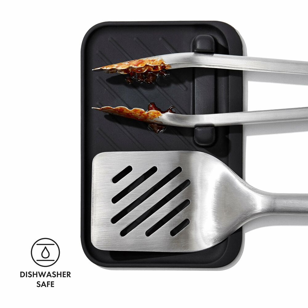 Metal spatula with tongs on a black surface, showing dishwasher safe feature.