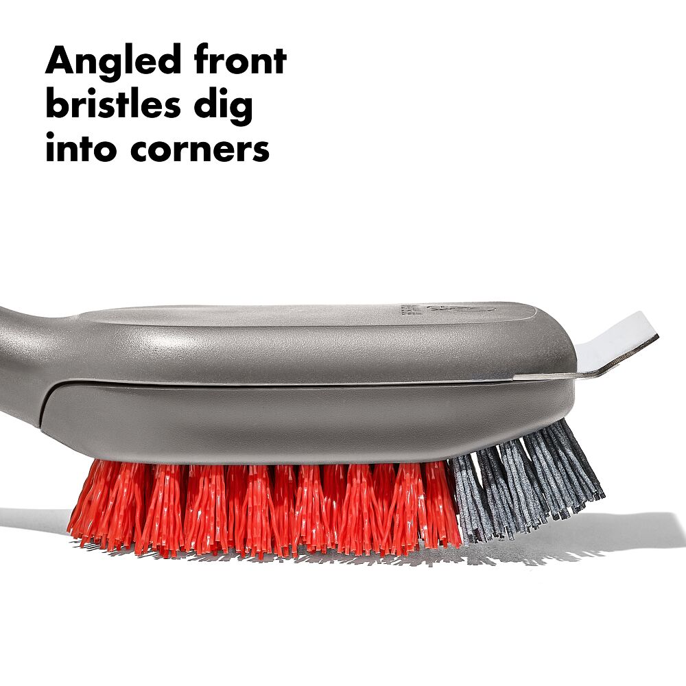 Gray brush with red bristles on a white background, highlighting angled front bristles.