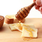 olive wood honey dipper being used with honey on cheese