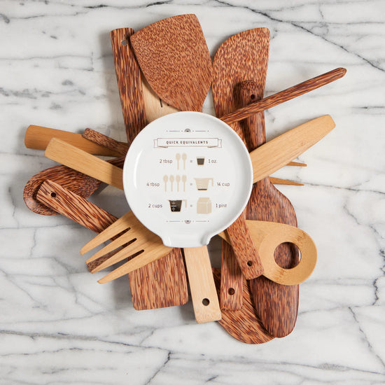Stoneware stove top spoon rest in a neutral white color with a quick equivalents pattern that features measuring conversions from tablespoon to ounces, tablespoon to cups and cups to pints.  