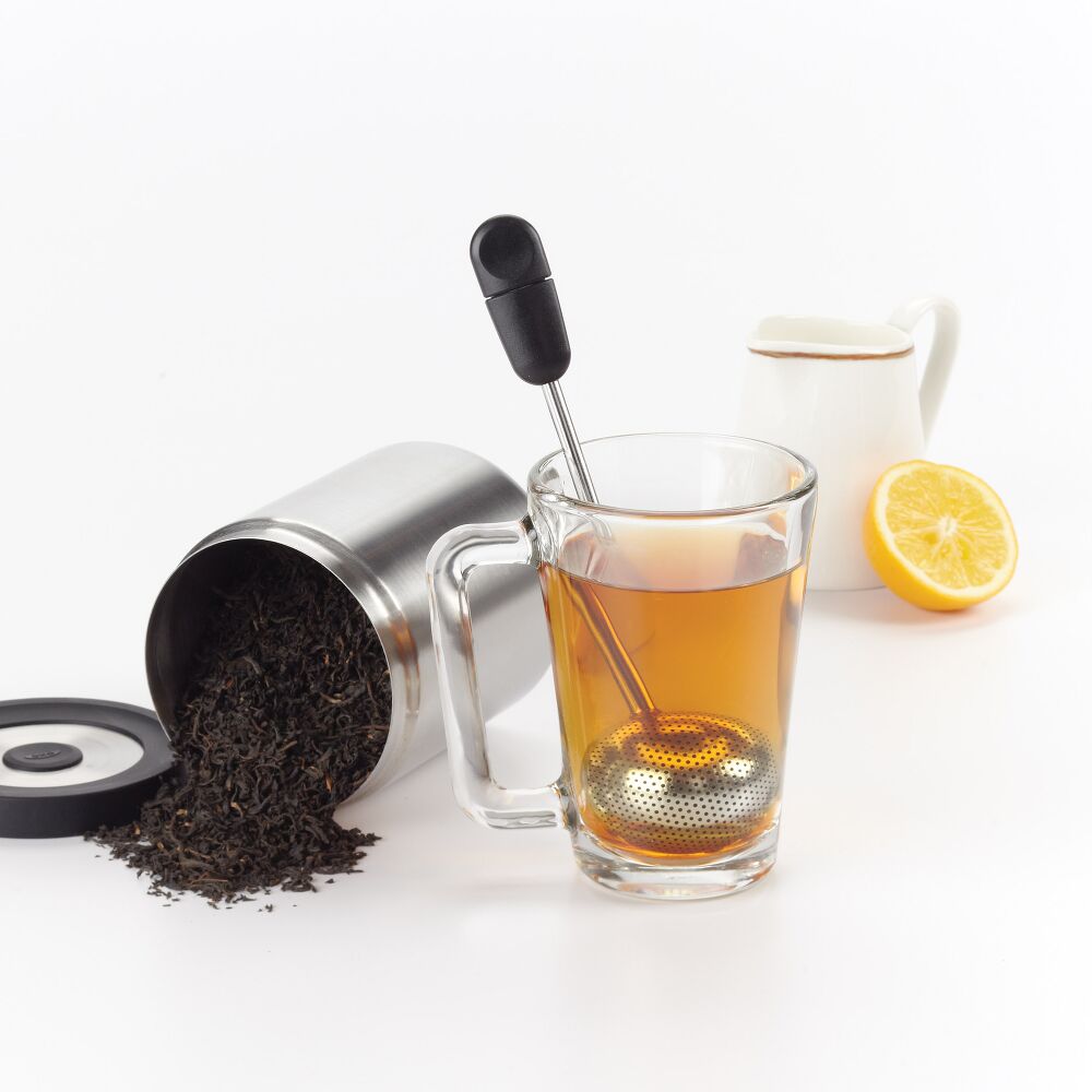 Tea-making setup with glass mug, tea leaves, and lemon on a white background