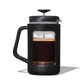 Black French press with coffee grounds and liquid on a white background