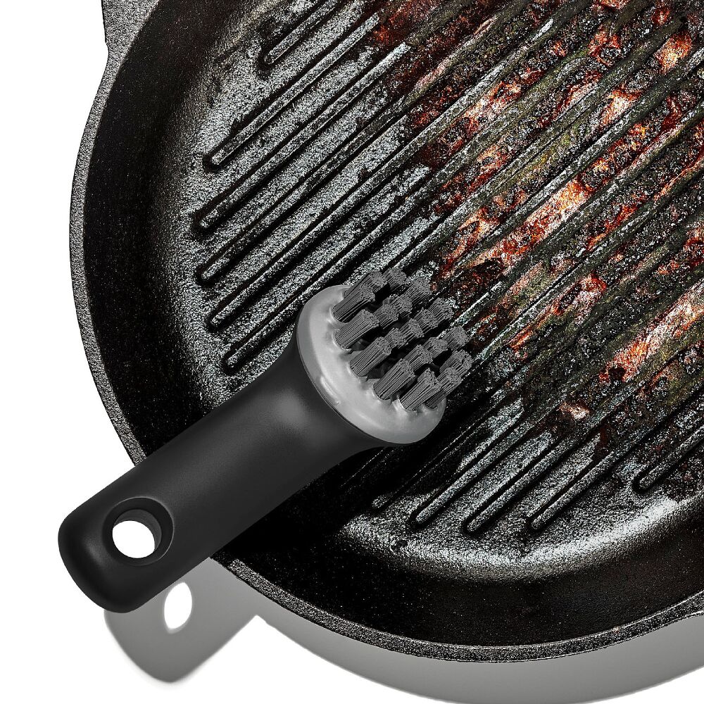 Black grill brush with bristle head on a cast iron grill pan
