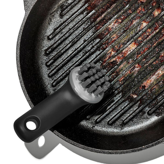 Black grill brush with bristle head on a cast iron grill pan