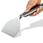 Hand holding a metal spatula with a black handle on a white background