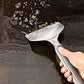 Person using a metal spatula to scrape oil from a hot surface