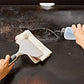 Person cleaning a cast iron skillet with a brush and cloth on a black surface.