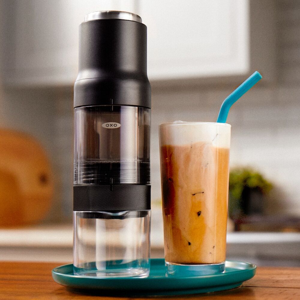 OXO coffee maker and iced coffee on a tray with a blurred kitchen background