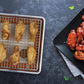 Baked chicken wings on a cooling rack and served with sauce on a black plate.