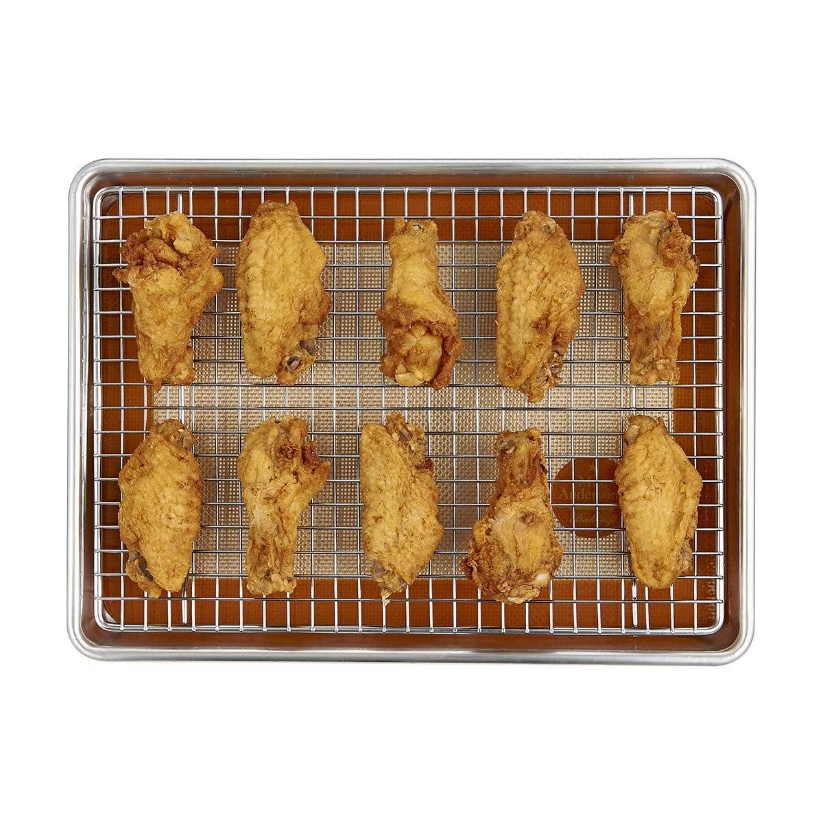 Fried chicken wings on a wire rack over a baking sheet with a white background