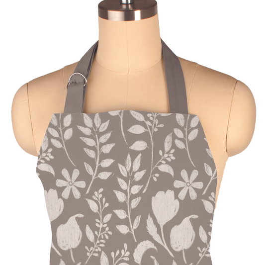 The MUkitchen&nbsp;Designer Apron in a white on gray botanical print, where style meets functionality in the kitchen. With the same classic tailoring as our beloved Classic Chef Apron, this apron showcases an on-trend design that will make a statement. 